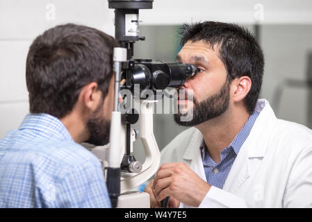 male doctor ophthalmologist is checking the eye vision of handsome young man in modern clinic. Doctor and patient in ophthalmology clinic .