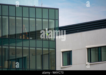 Construction worker on phone behind glass wall Stock Photo