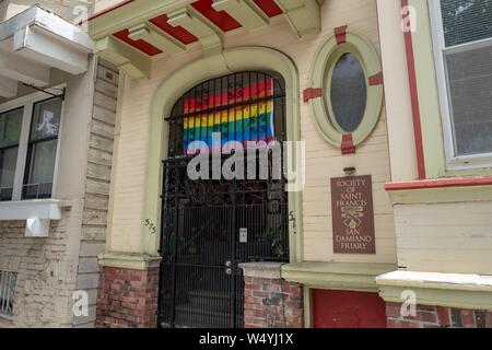 Facade with sign at monastery for Society of Saint Francis, an order of Franciscan monks in the Mission District neighborhood of San Francisco, California, with rainbow pride flag visible, July 18, 2019. () Stock Photo