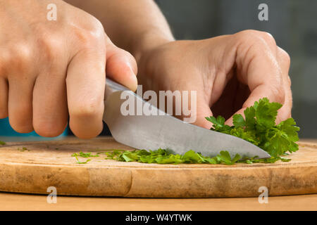 hands of woman chopping parsley leaves on the wooden cutting board Stock Photo