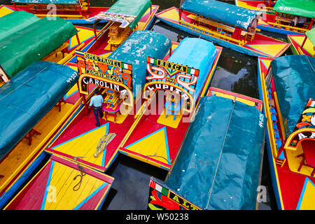 Xochimilco, Mexico City, June 25, 2019 - Trajineras moored in Nativitas Embarcadero with one man on the boat. Group of boats in Xochimilco canal. Stock Photo