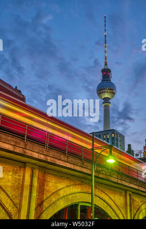 The famous Television Tower in Berlin at dusk with a motion blurred commuter train Stock Photo