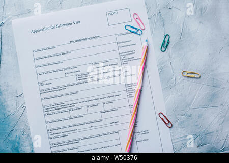 Filling the Schengen Visa Application Form from above. Multicolored paper clips and pen. Stock Photo