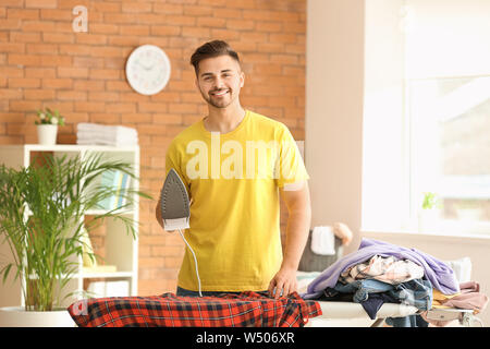 Handsome young man ironing clothes at home Stock Photo