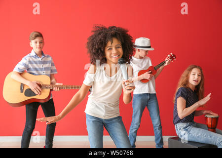 Teenage musicians playing against color wall Stock Photo