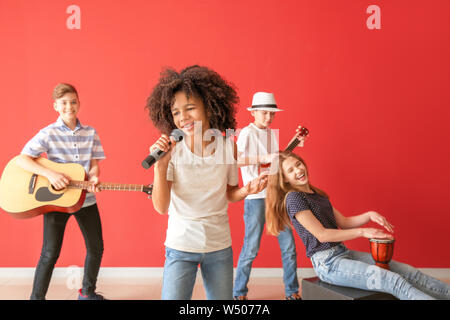 Teenage musicians playing against color wall Stock Photo