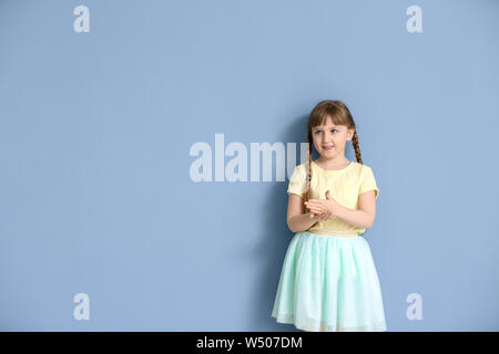 Cute deaf mute girl using sign language on color background Stock Photo