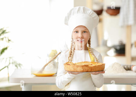 Cute little chef with pie in kitchen Stock Photo