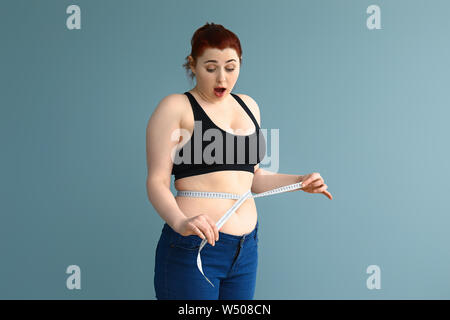 Surprised excess weight caucasian woman wrap measure tape around her waist.  High quality photo image. Stock Photo by ©kazzakova 558018968