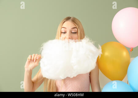 Beautiful woman with cotton candy and air balloons on color background Stock Photo