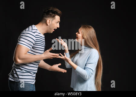 Young quarrelling couple on dark background Stock Photo
