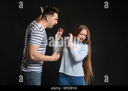 Young quarrelling couple on dark background Stock Photo