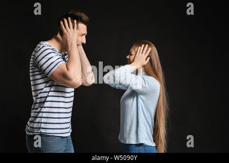 Young quarrelling couple on dark background Stock Photo