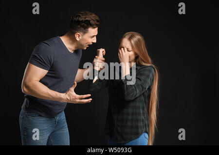Young quarrelling couple on dark background Stock Photo