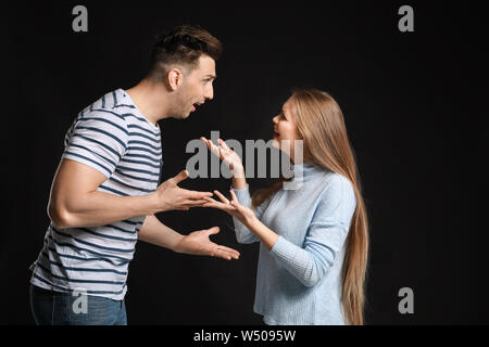 Young quarrelling couple on dark background Stock Photo