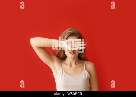 Young woman covering her eyes on color background Stock Photo