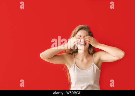 Young woman covering her eyes on color background Stock Photo