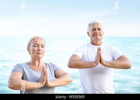 Mature couple practicing yoga at sea resort Stock Photo