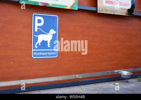 'Dog parking station' for dogs waiting for owners outside of shops, with blue sign showing dog on leash, hooks for attaching leash and water bowls Stock Photo