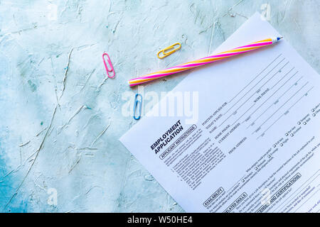 Standard Application for Employment. HR, Hiring, Applying concept. Job Application form. Top view. Multicolored paper clips and pen. Stock Photo