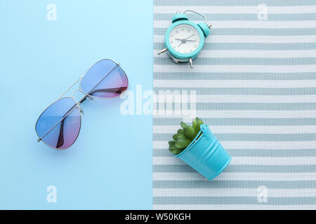 Stylish sunglasses with alarm clock and plant on color background Stock Photo