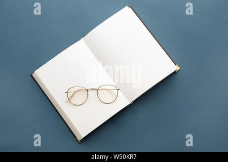Open book with eyeglasses on grey background Stock Photo