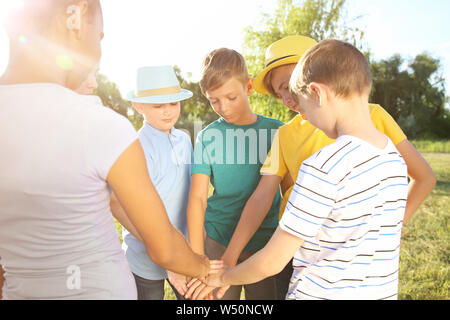 Children putting hands together outdoors Stock Photo