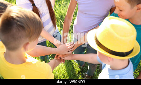 Group of children putting hands together outdoors Stock Photo