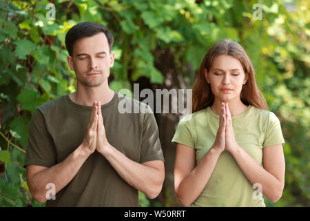 Religious couple praying to God outdoors Stock Photo