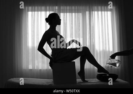 Spa therapist washing legs of young woman in beauty salon Stock Photo