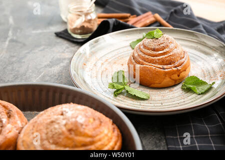 Plate with tasty cinnamon bun on grey table Stock Photo