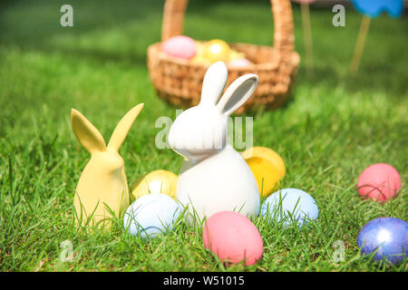 Easter eggs with ceramic bunnies on grass outdoors Stock Photo