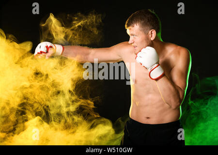 Strong male boxer in smoke on dark background Stock Photo