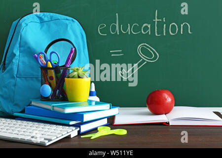 Set of school supplies with backpack on table in classroom Stock Photo