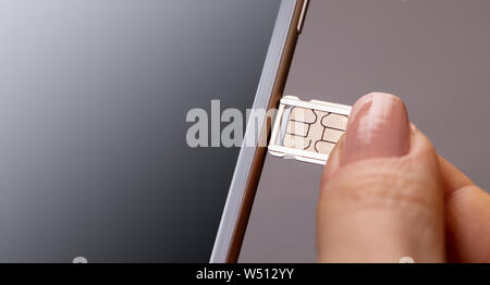 sim card and mobile phone in female hands Stock Photo