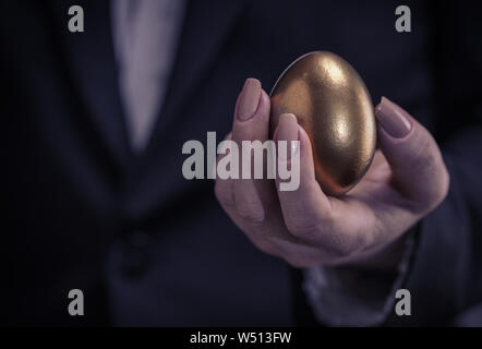 golden chicken egg in female hand closeup Stock Photo