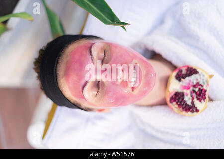 Top view of a woman's face with a pomegranate mask - Relaxed girl in the spa - Portrait Stock Photo