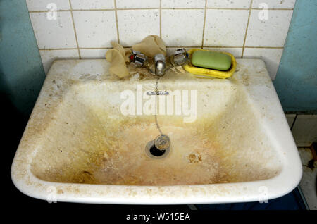 Messy bathroom sink, with dirty tap, soap and wall. Stock Photo