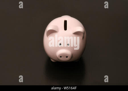 Pink piggy Bank in the shape of a pig stands in the center on a black background. black Friday Stock Photo