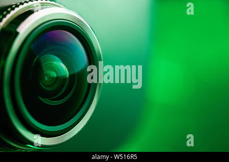 Camera lens with green backlight. Side view of the lens of camera on green background. Greencamera Lens close Up. Pure red Stock Photo