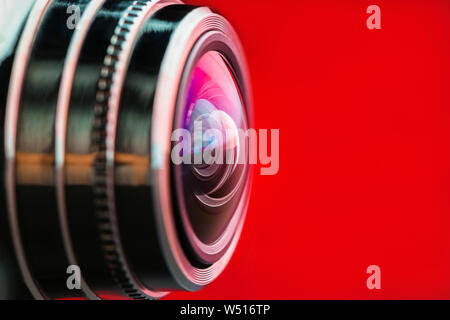 Camera lens with red backlight. Side view of the lens of camera on red background. Red  camera Lens close Up. Gorizontal photo Stock Photo