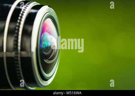 Camera lens and  green backlight. Side view of the lens of camera on green background. Camera Lens Close Up. Optics Stock Photo