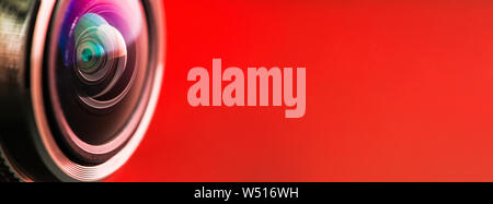Banner. Camera lens with red backlight. Side view of the lens of camera on red background. Camera Lens close Up. Optics Stock Photo