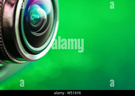 Camera lens and green backlight. Side view of the lens of camera on green background. Camera Lens Close Up. Optics Stock Photo