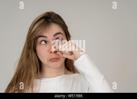 Portrait of beautiful teenager girl with funny sad faces looking sweet and cute. Millennial female making silly unhappy gestures isolated on neutral b Stock Photo