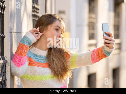 Pretty teenager girl taking selfie happy and excited in the city. Young student woman recording video of herself blogging outdoors In Millennial gener Stock Photo