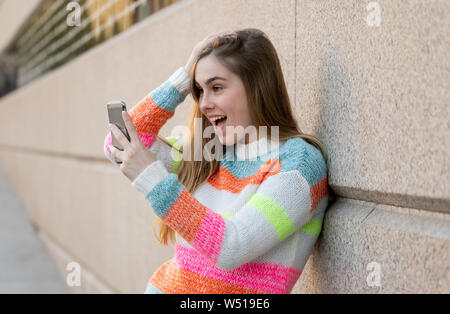Pretty teenager woman happy and excited on smart mobile phone checking surprised lots of likes and followers on her blog. Urban background. In technol Stock Photo