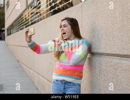 Happy pretty teenager girl using smart mobile phone excited blowing a kiss and waving to followers friends or family recording video or chatting. Vide Stock Photo