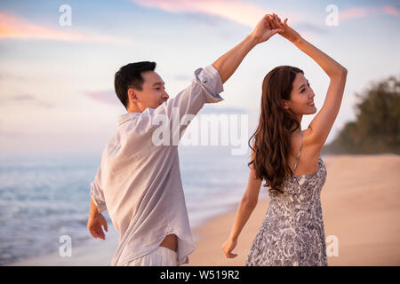 Happy young couple dancing on beach Stock Photo