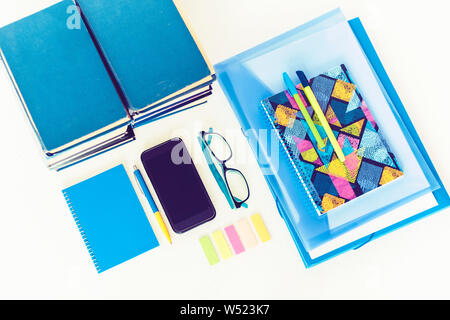 Back to school background. Stationery accessories – notebooks, plastic folder, pens, stickers, glasses with smartphone and stack of books education co Stock Photo